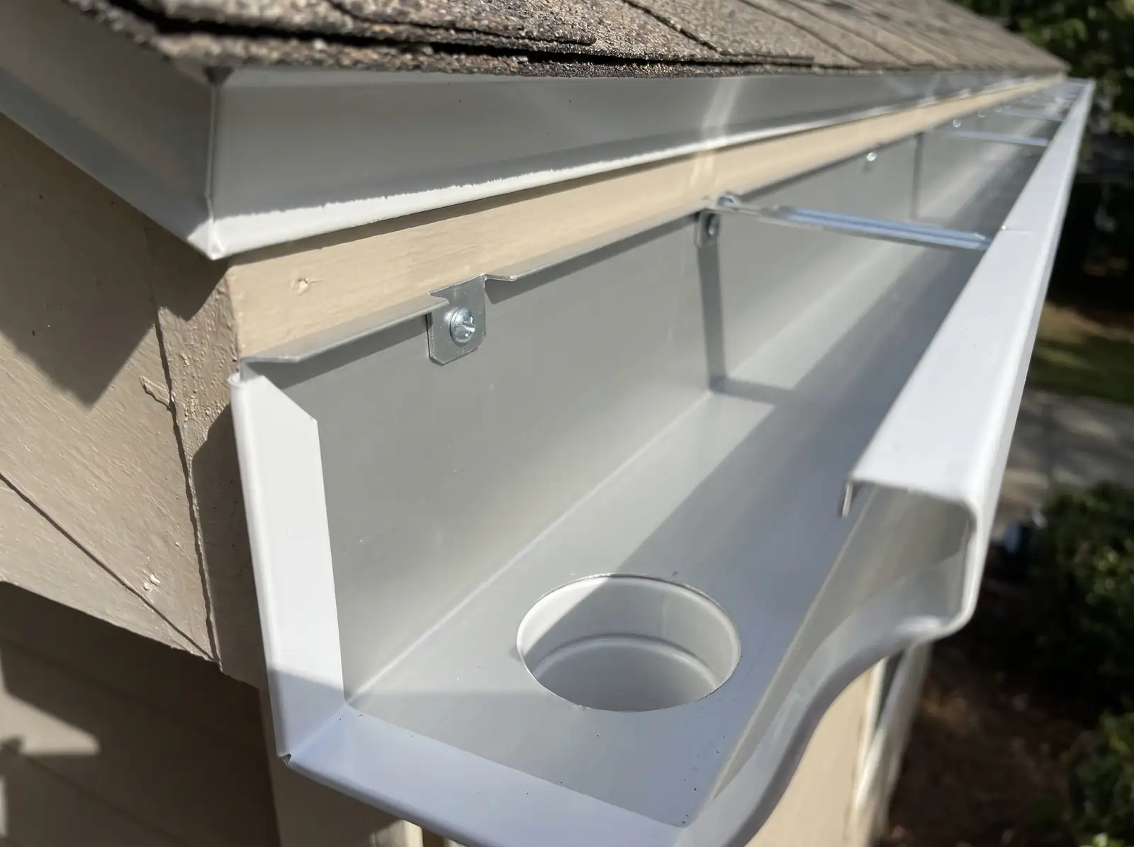 Inside a new white gutter with a hidden hanger, screws and a round downspout outlet